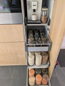 Organisation d’un espace tisanerie fonctionnel avec machine à café intégrée dans un placard pour réduire le bruit et stockage des légumes secs en bocaux hermétiques