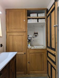 Transformation d’une porte ancienne en meuble multifonction intégrant une table à langer et un espace buanderie optimisé avec cumulus intégré